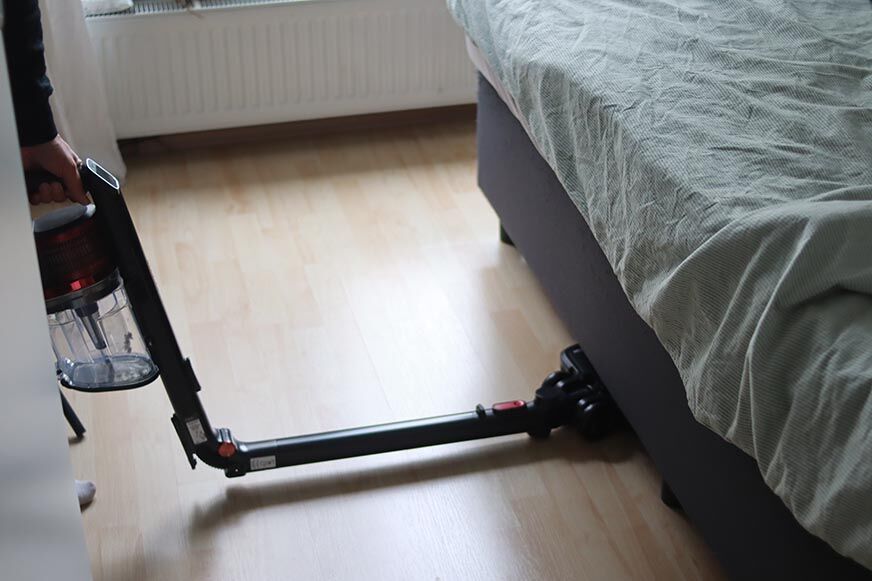 Man sieht den Shark Anti Hair Wrap Flexoloxy bei der Reinigung unter Möbeln.